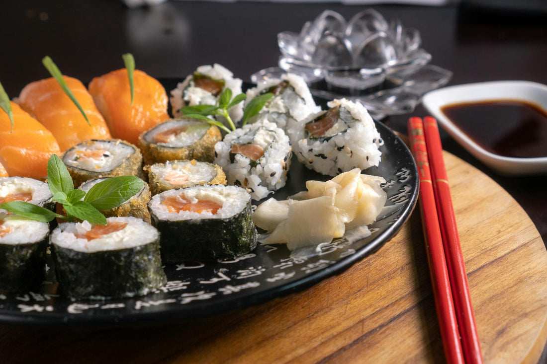 A mouth-watering assortment of sushi served with soy sauce, garnished with fresh herbs, and chopsticks on a wooden board.
