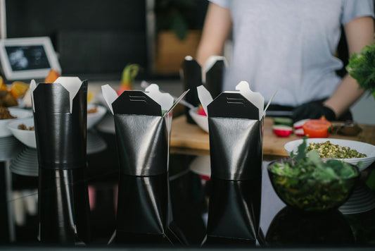 Stylish black takeout boxes on a contemporary kitchen counter, ready for takeaway.